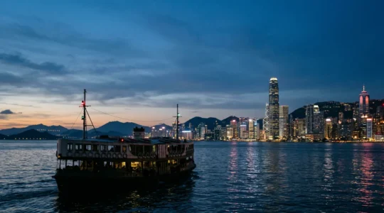 Hong Kong ferry navigating between islands at twilight with city skyline in background