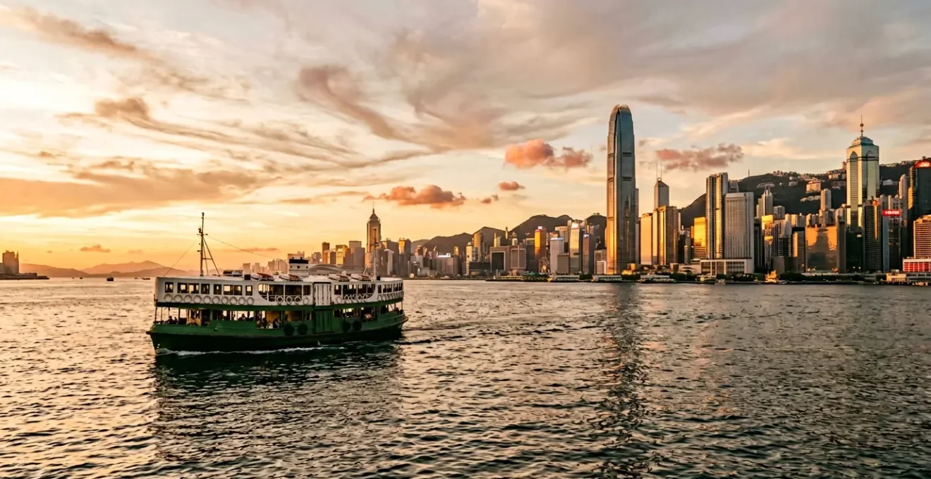 Iconic Star Ferry crossing Victoria Harbour with Hong Kong skyline at golden hour