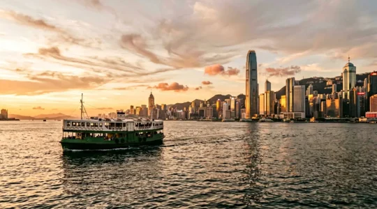 Iconic Star Ferry crossing Victoria Harbour with Hong Kong skyline at golden hour