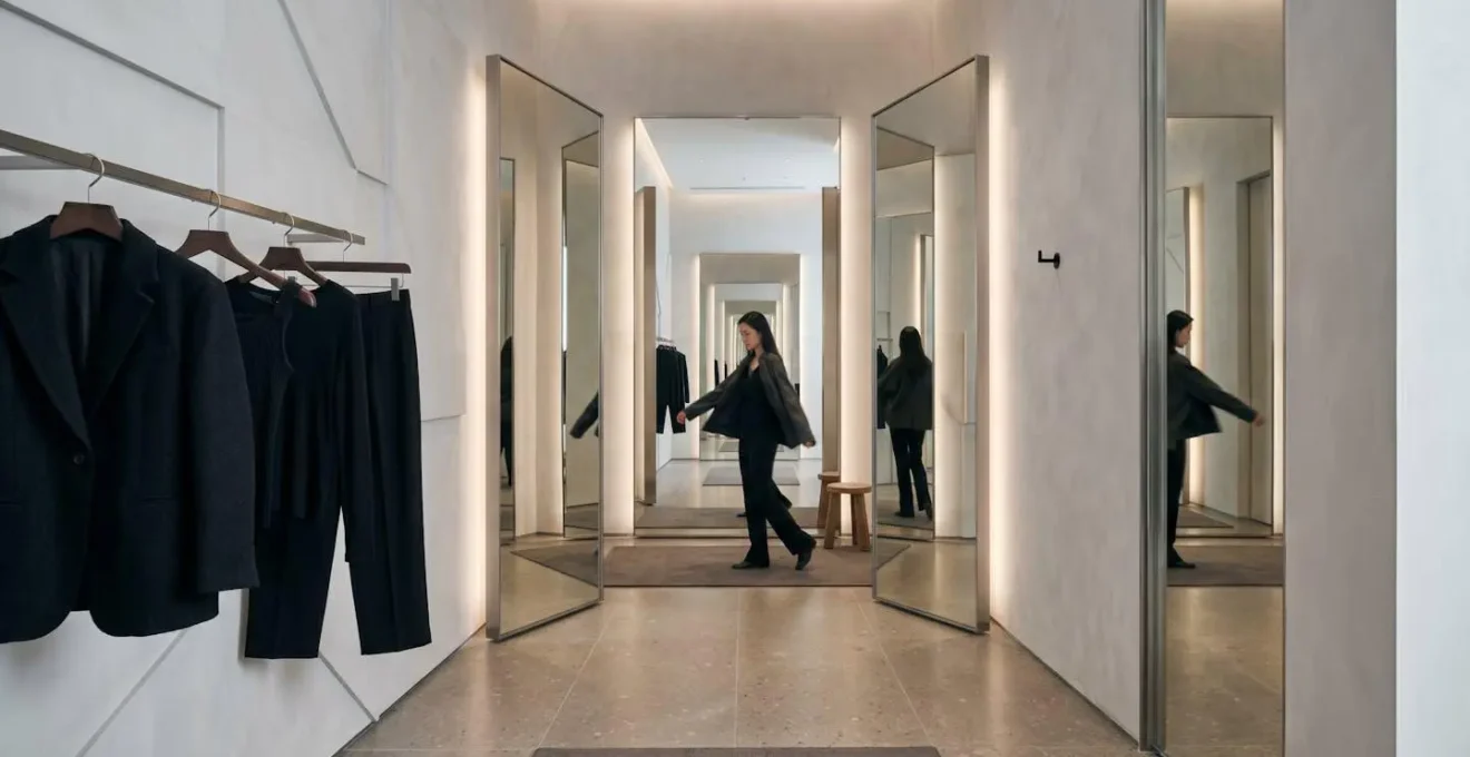 Shopper examining clothing fit in a modern Hong Kong boutique fitting room with multiple angle mirrors