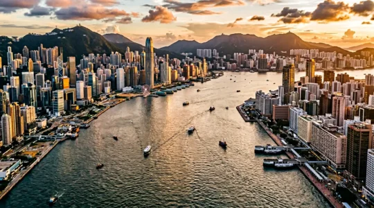 Split panoramic view of Hong Kong Island skyline and Kowloon waterfront at golden hour