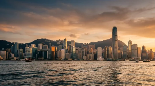 Luxurious Hong Kong harbor view with two iconic hotels reflected in the water at golden hour