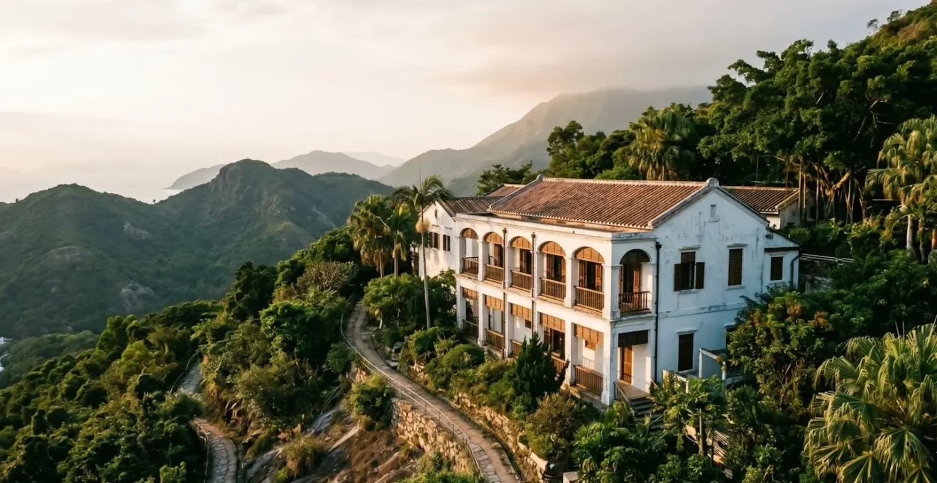 Former colonial police station converted into boutique hotel, captured at golden hour with its distinctive white colonial architecture against lush hillside backdrop