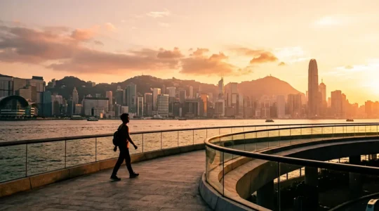 Traveler viewing Hong Kong Island skyline from TST waterfront at golden hour